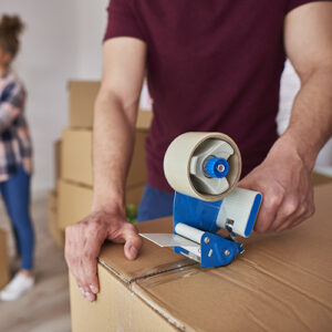 Man with adhesive tape packing boxes
